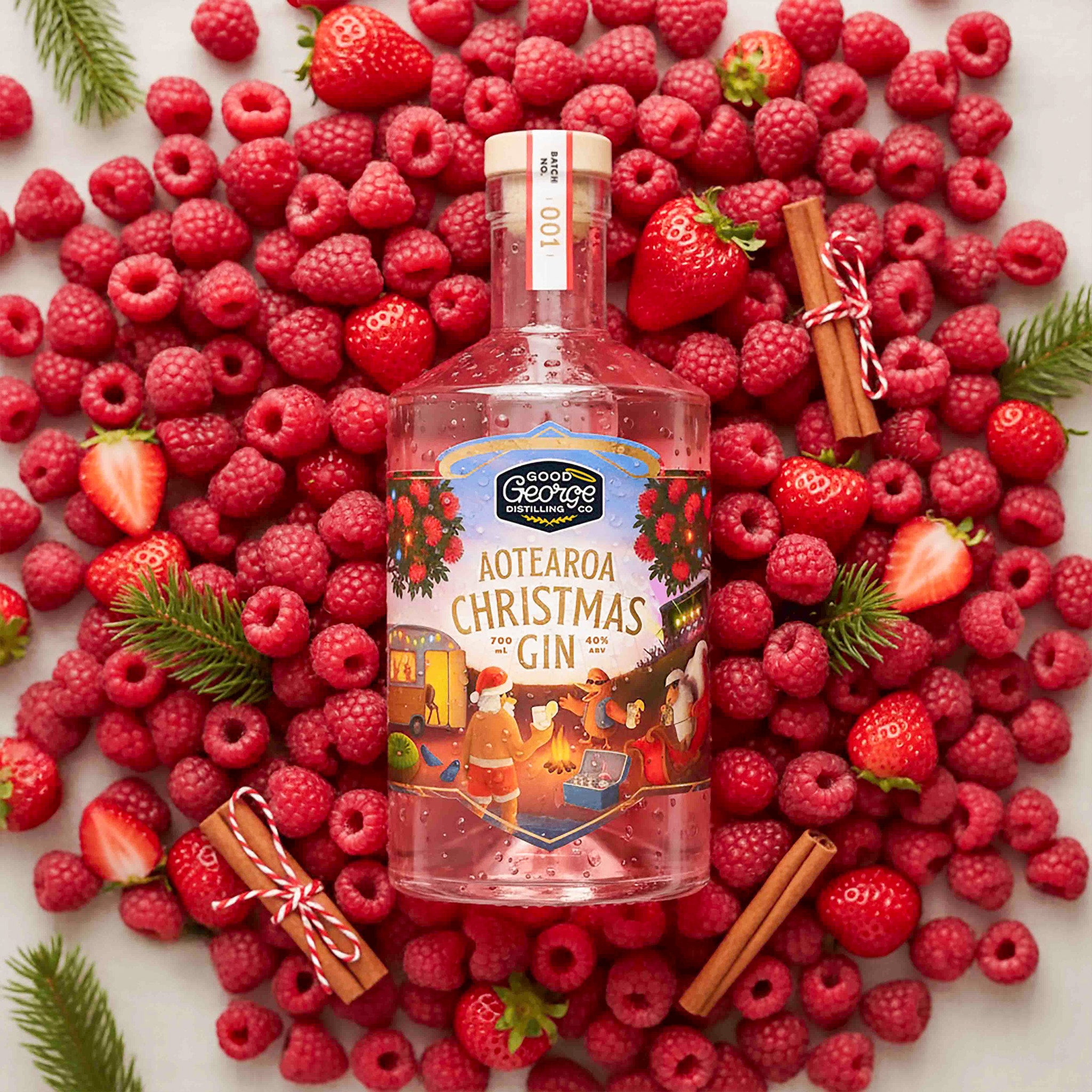 A bottle of Aotearoa Christmas Gin surrounded by raspberries and strawberries on a white background.