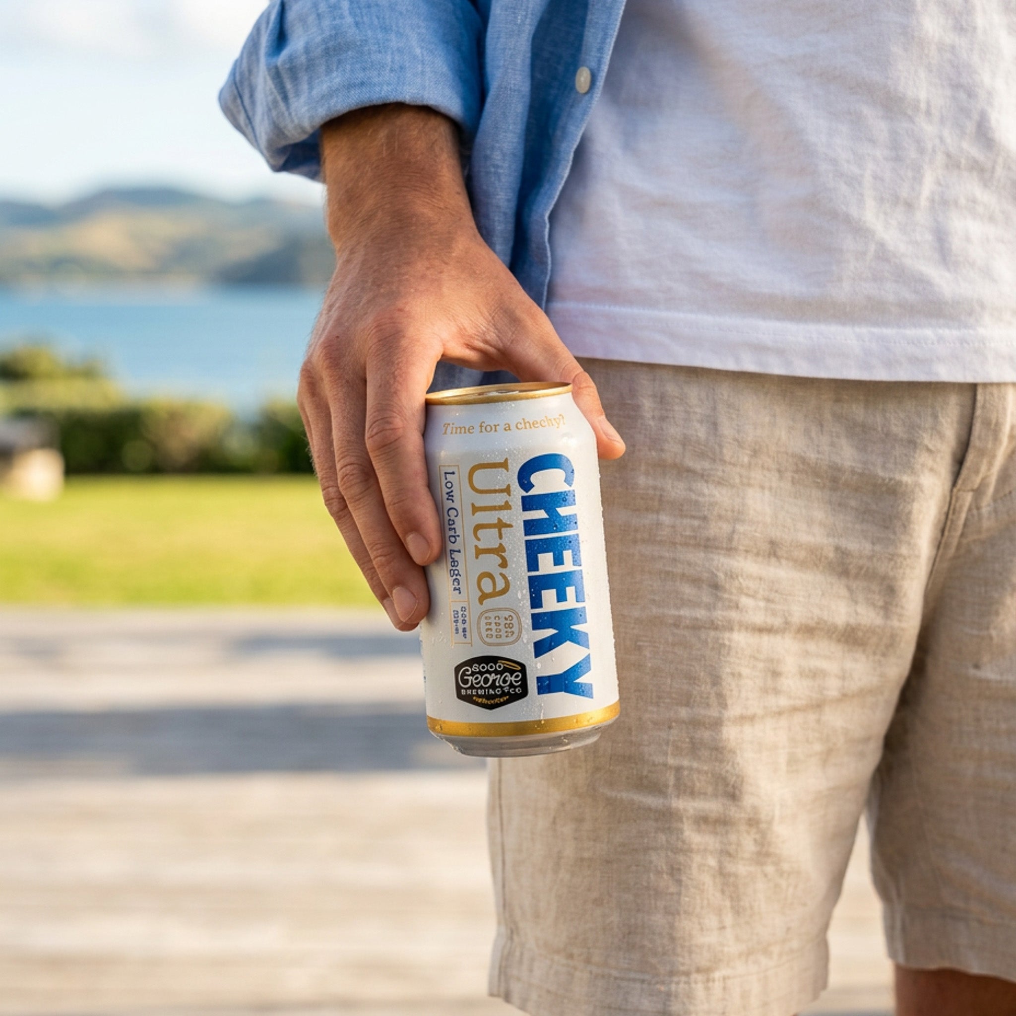 Person holding a can of Cheeky Ultra beer with a scenic background