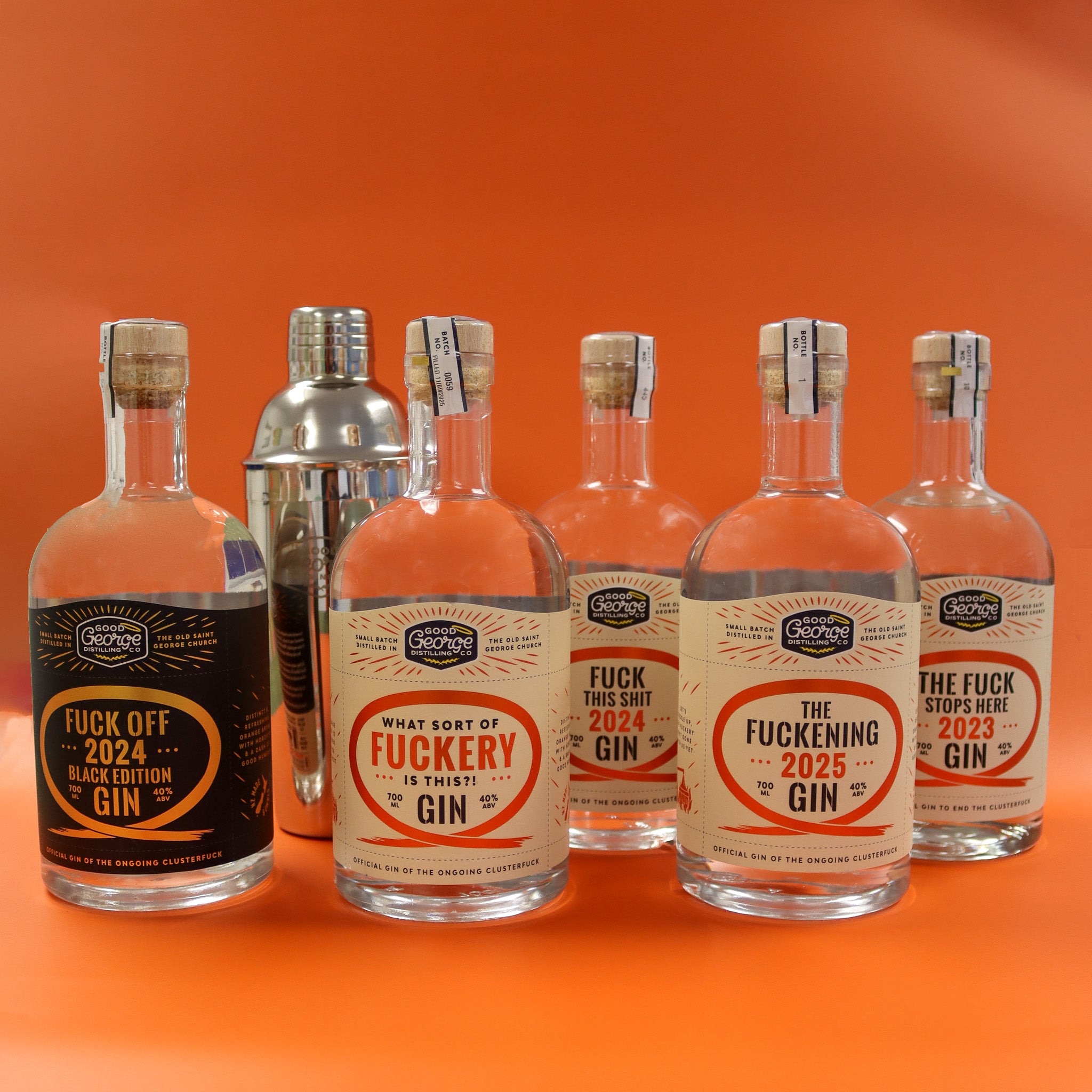 Five bottles of 'The Fucking Gin' with humorous labels on an orange background