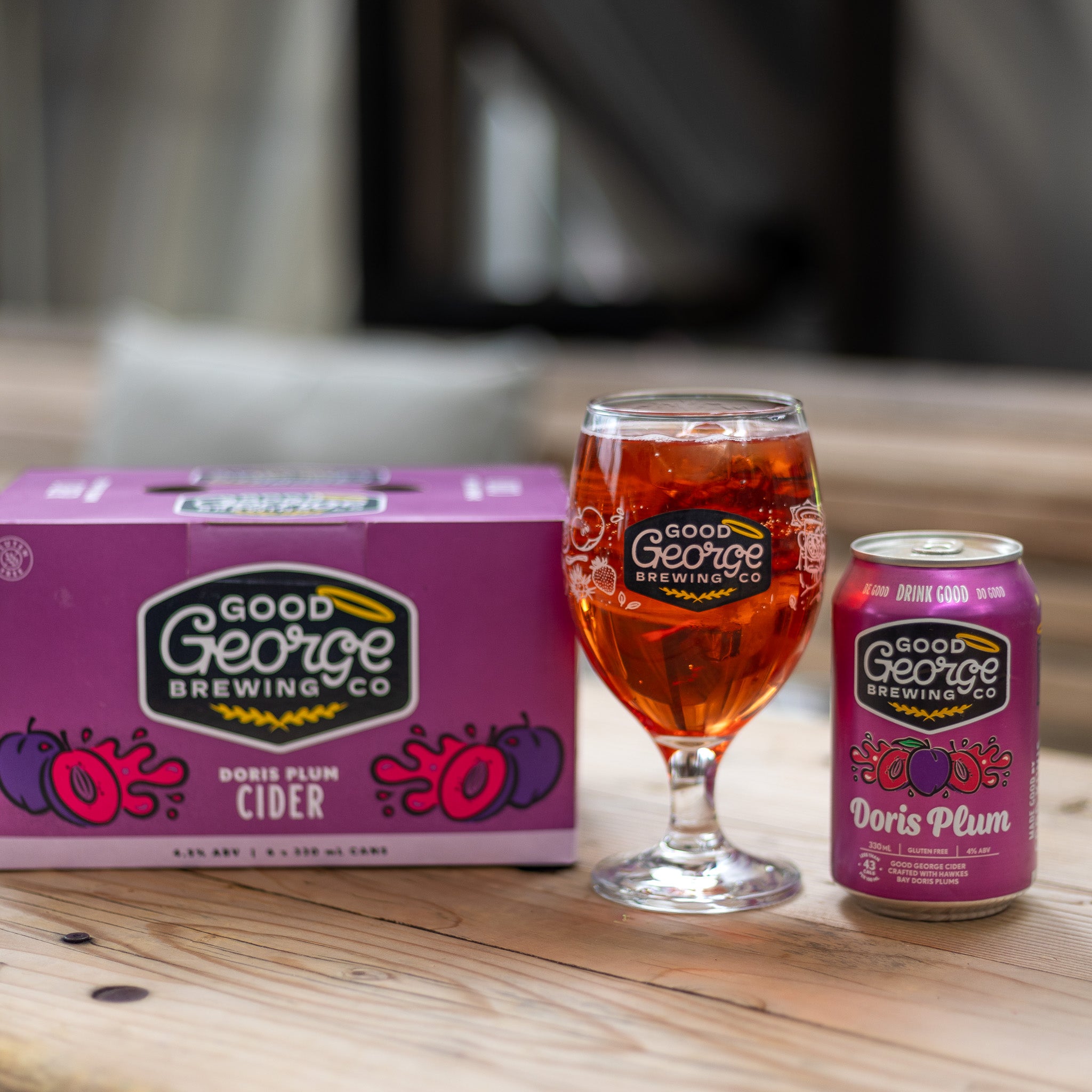 A product image featuring Doris Plum cider cans and packaging with branding and plum graphics on a purple background and a glass next to it.