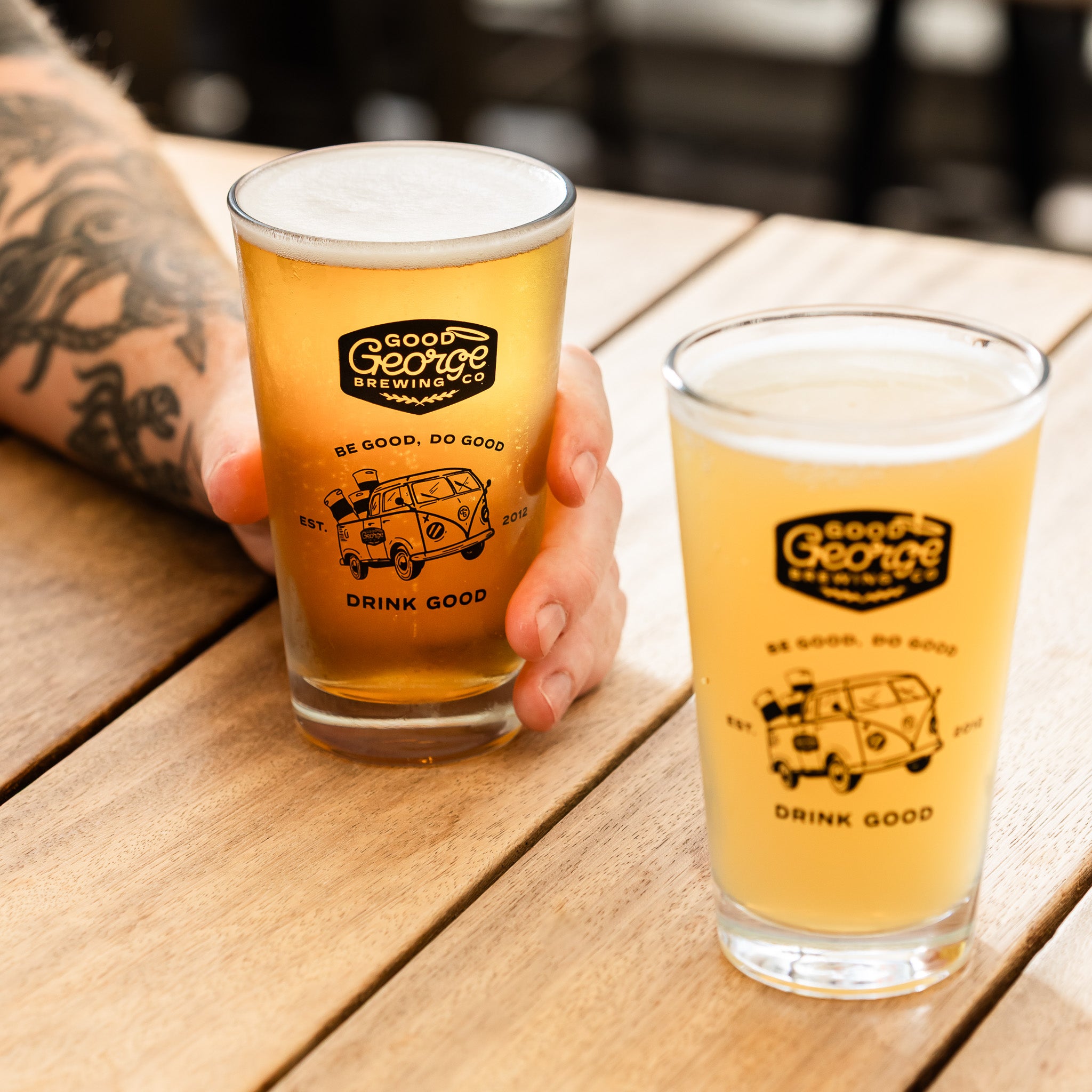 Two glasses of beer from Good George Brewing Co on a wooden table.
