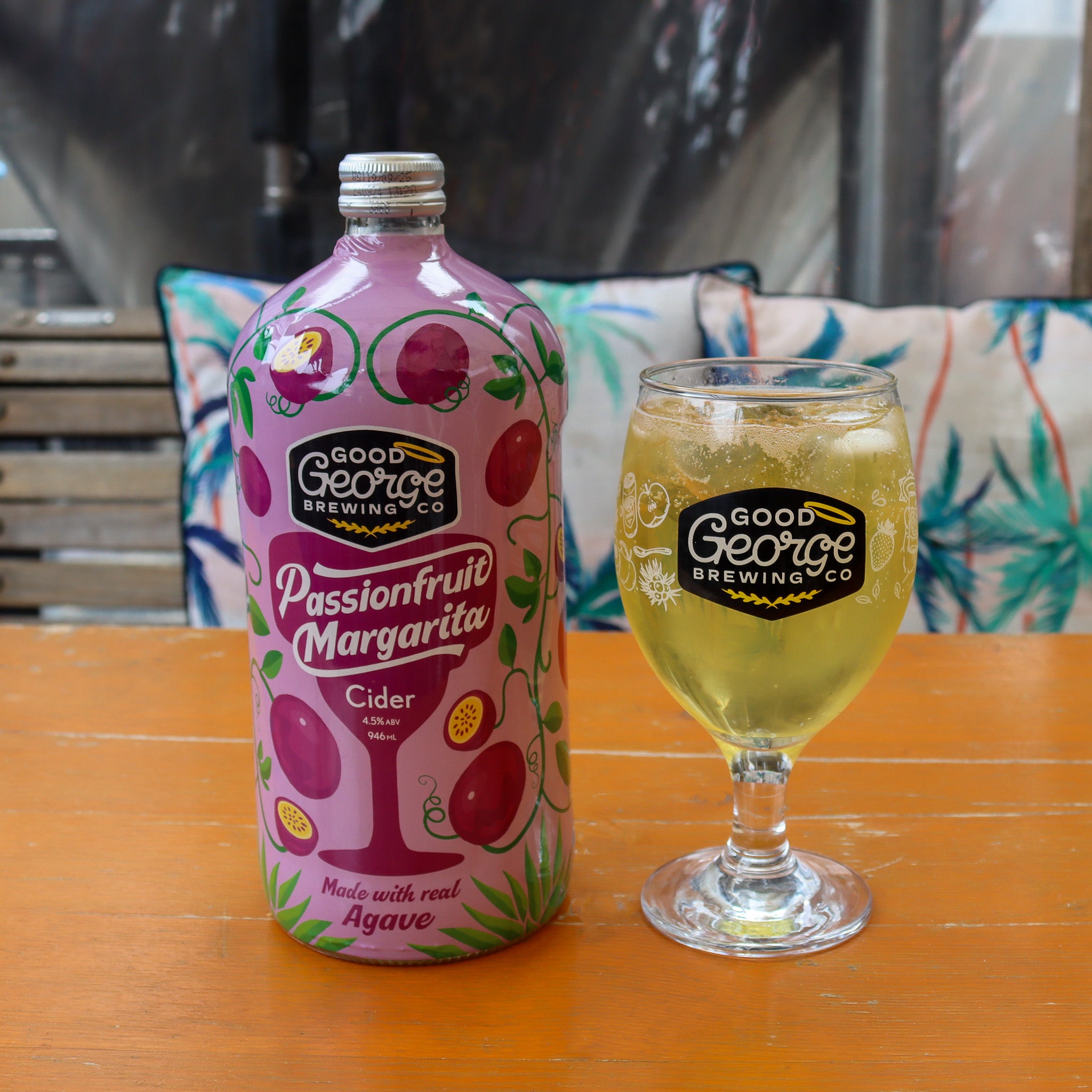 A bottle of Passionfruit Margarita Cocktail Cider with a Good George glass of cider next to it.