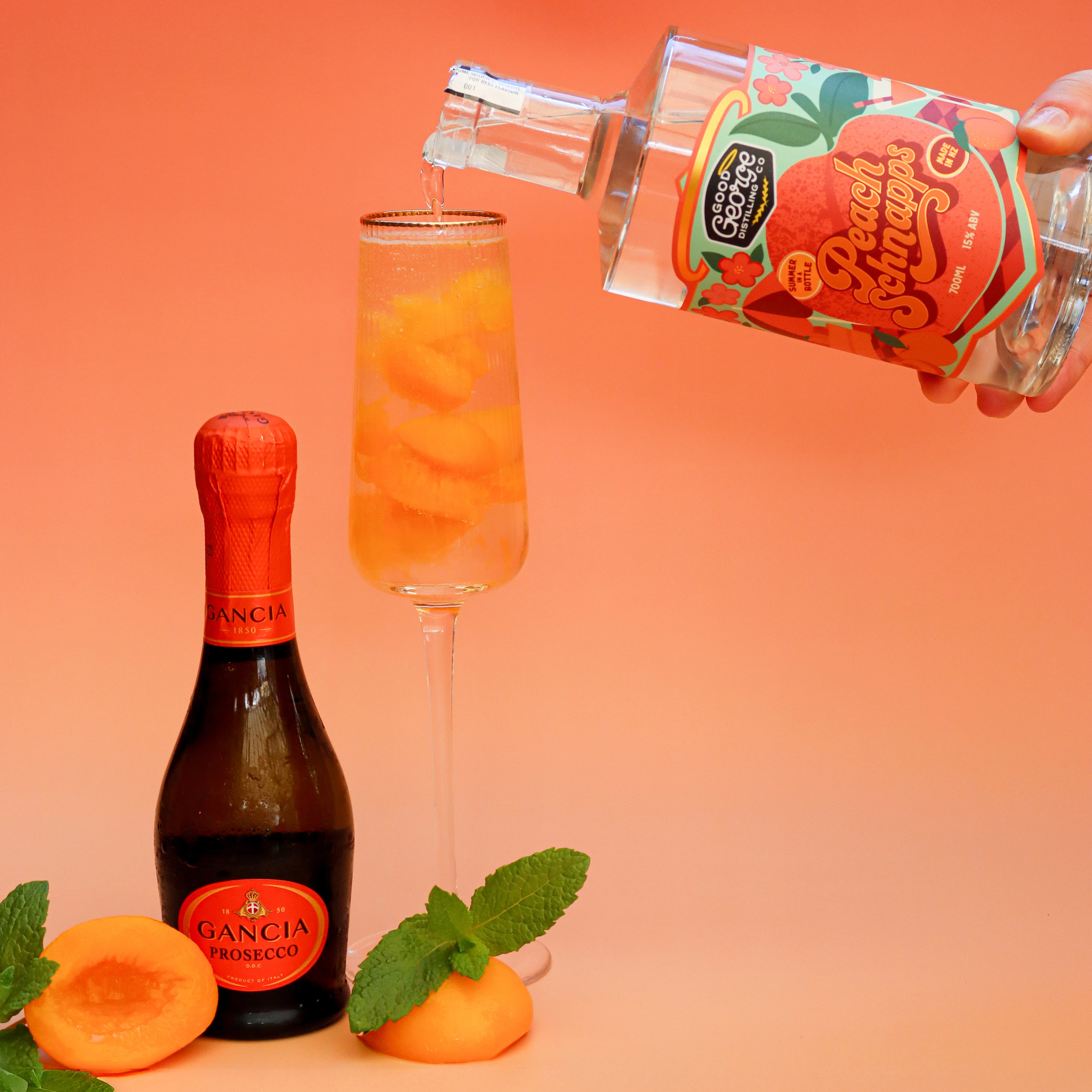 Bottle of Gancia Prosecco and a glass with peach slices being poured, on an orange background.