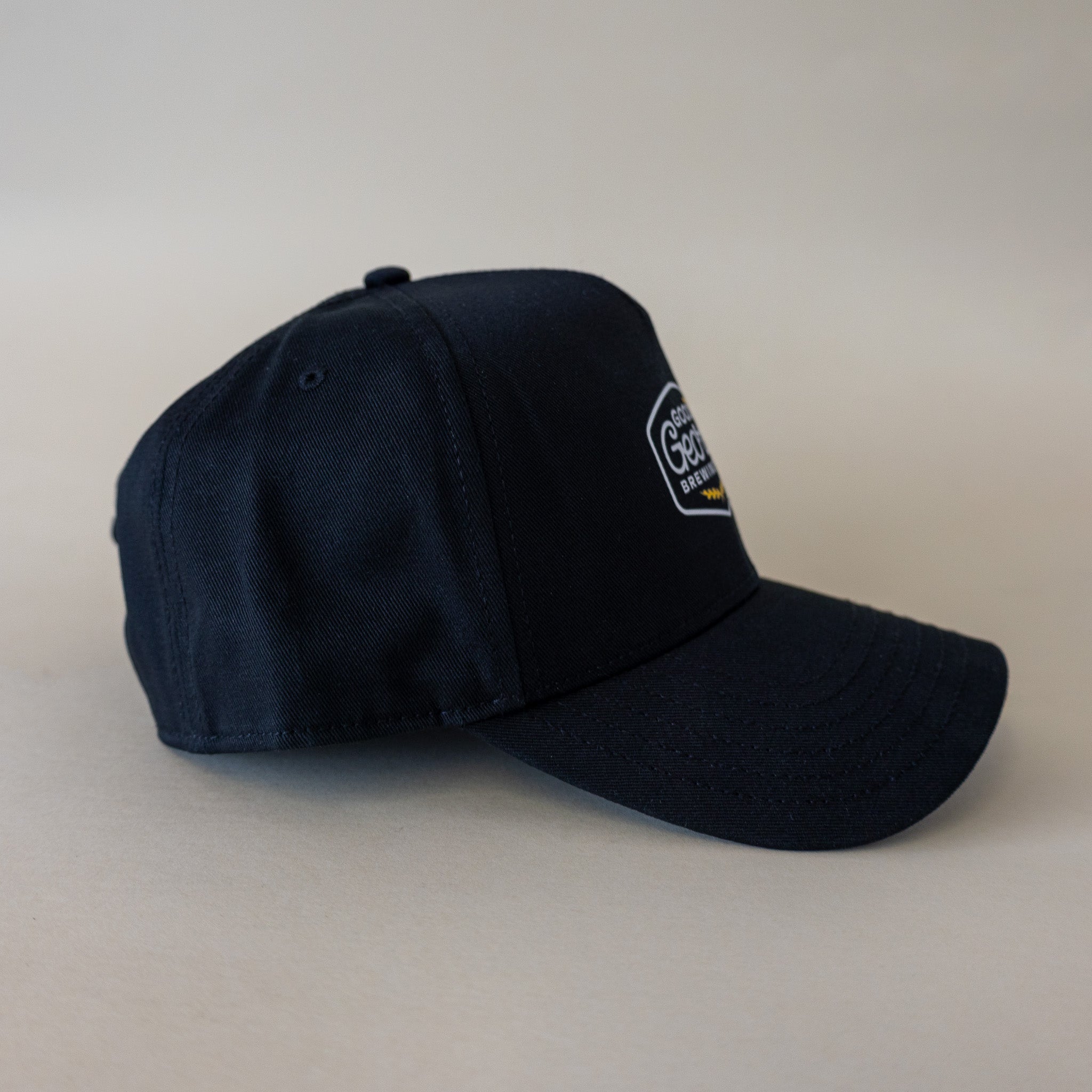 A black George snapback cap with a curved peak and an embroidered logo on the front.