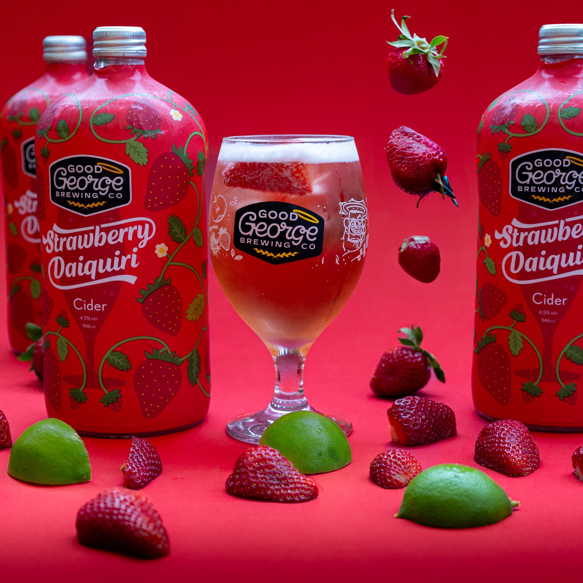 3 bottles of Strawberry Daiquiri Cider with a glass of cider next to it and lime and strawberries surrounding it.