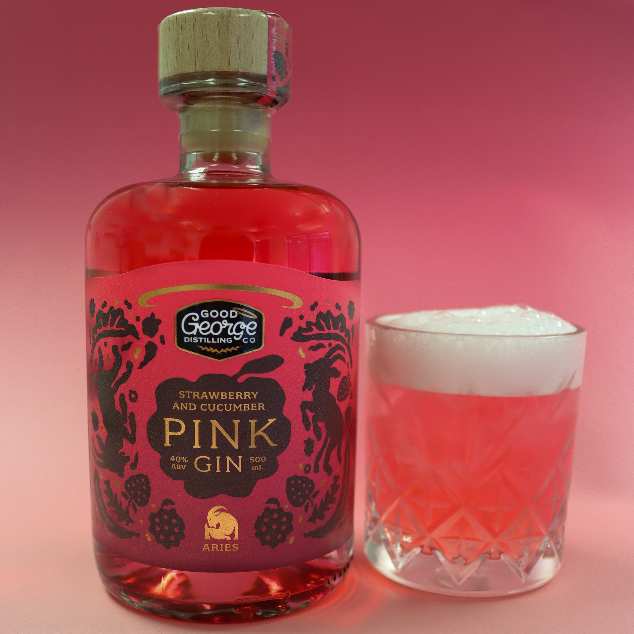 Bottle of Good George Strawberry and Cucumber Pink Gin with a glass of pink cocktail on a pink background