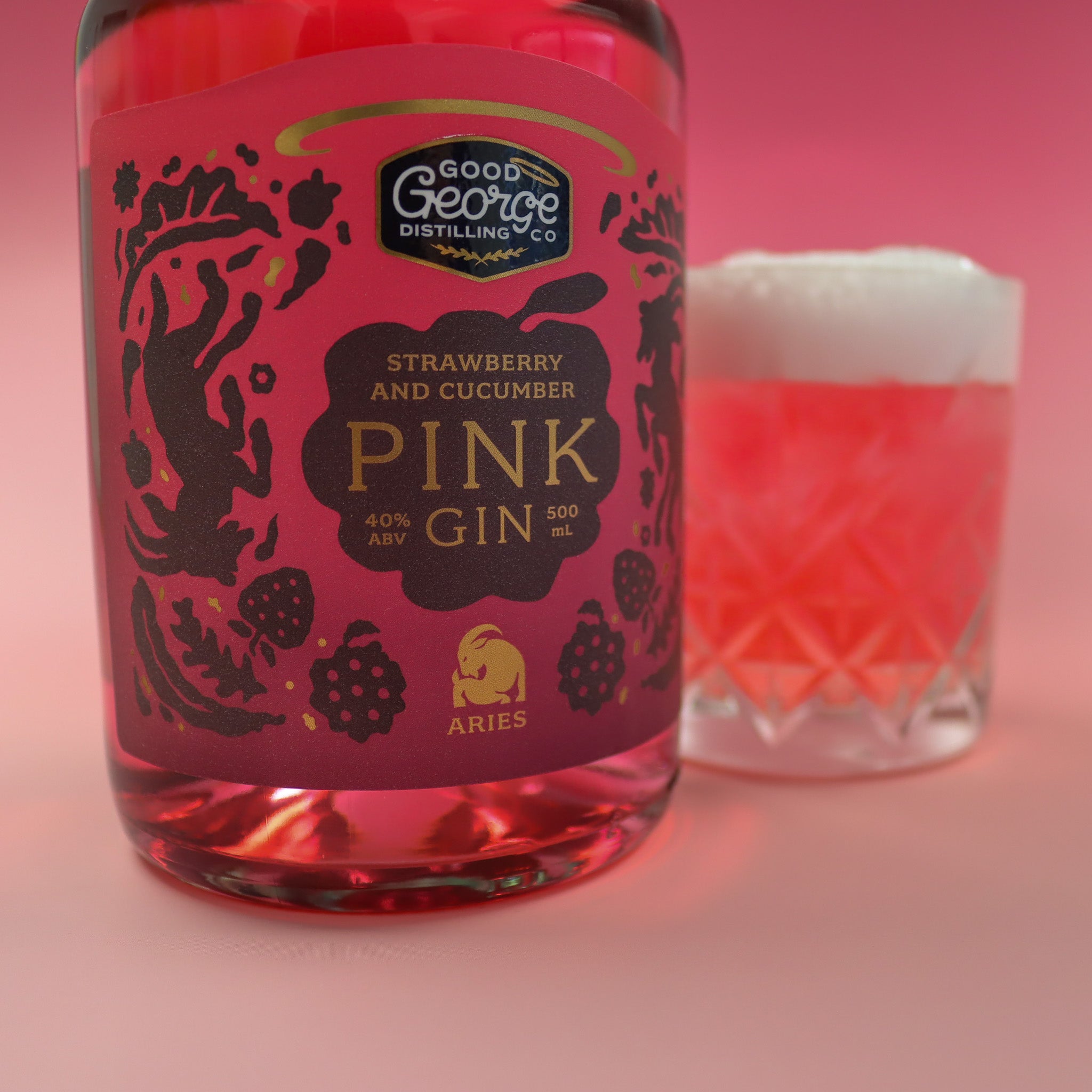 Bottle of Good George Strawberry and Cucumber Pink Gin with a glass of pink cocktail on a pink background