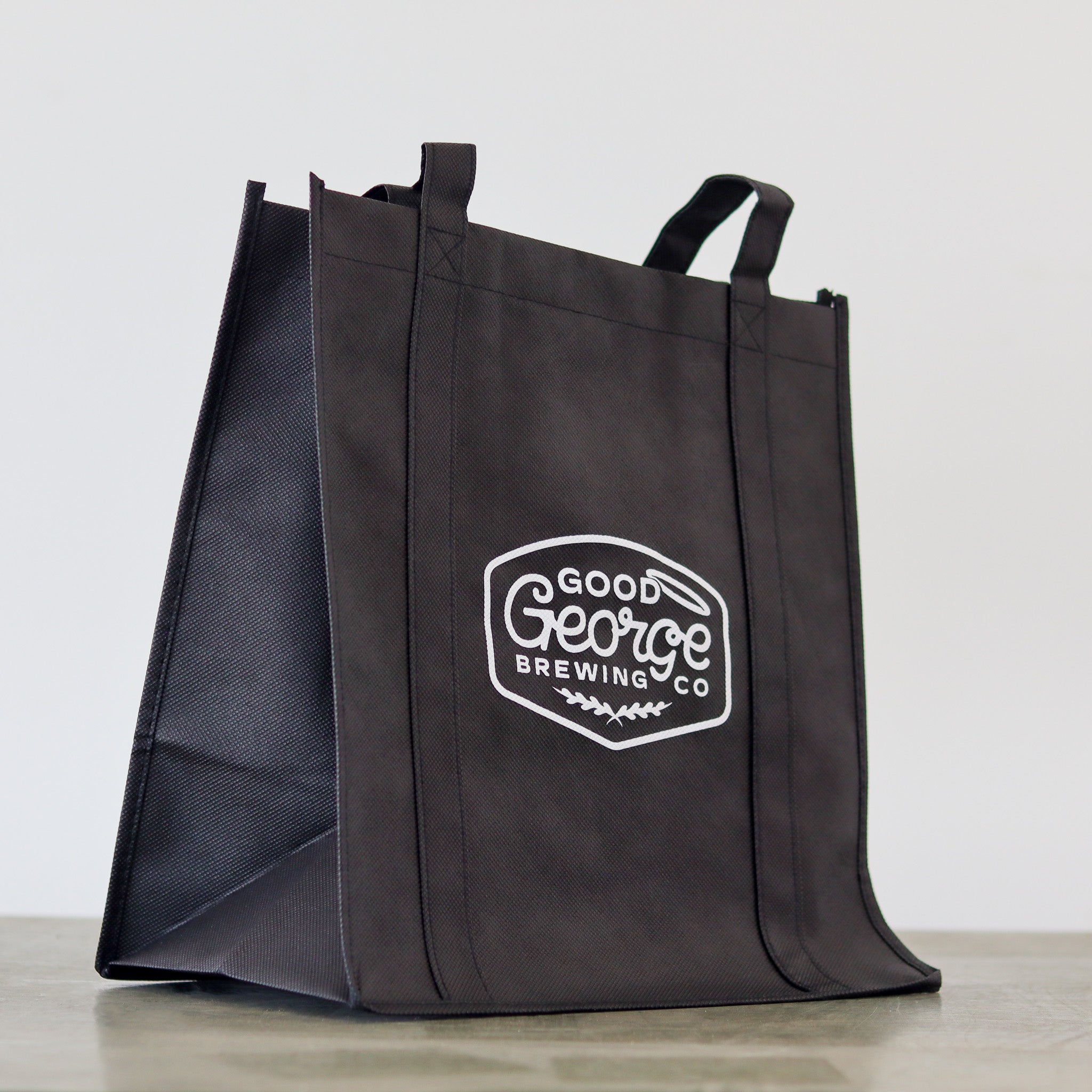 A black Good George tote bag with the brand's logo printed in white.