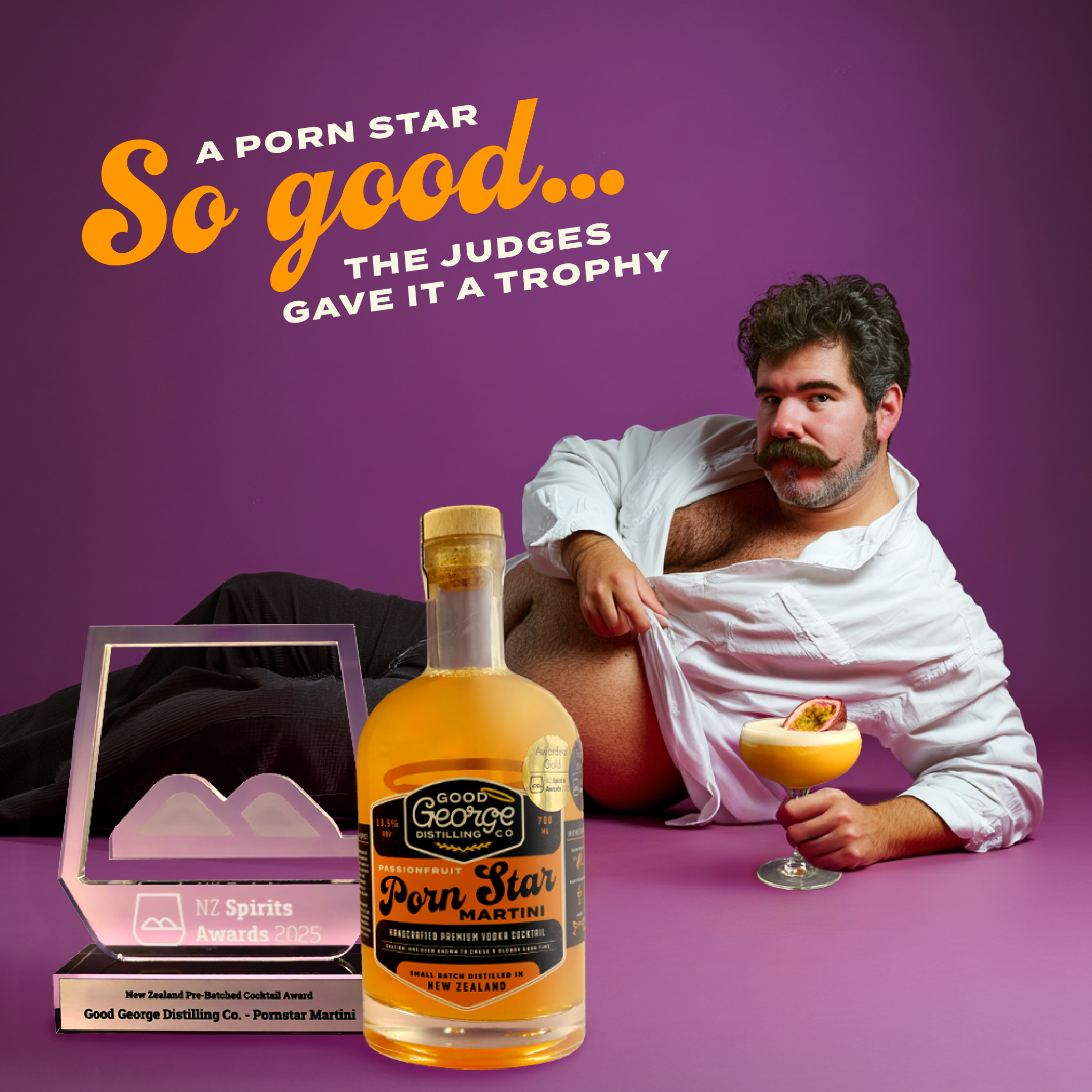 Bottle of 'Good George' Porn Star Whisky with a man holding a cocktail on a purple background.