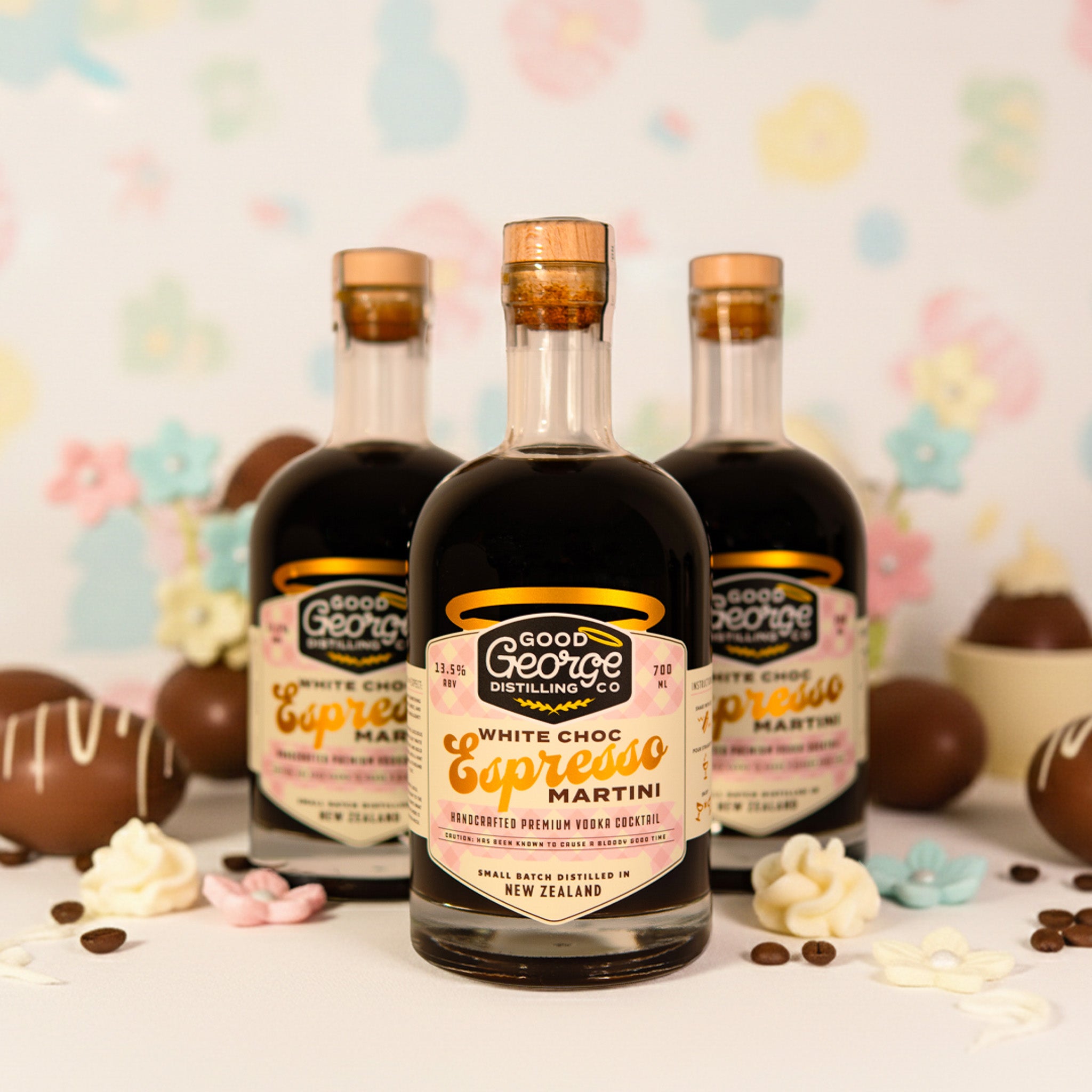 Three bottles of Good George Distilling Co. White Choc Espresso Martini with decorative items on a colorful background.