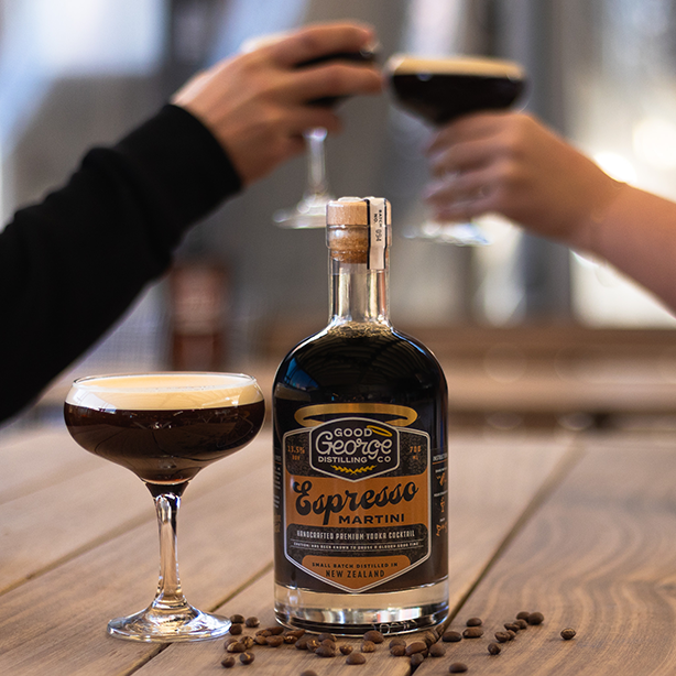 Bottle of Good George Distilling Co. Espresso Martini with two glasses filled with the cocktail on a wooden surface.