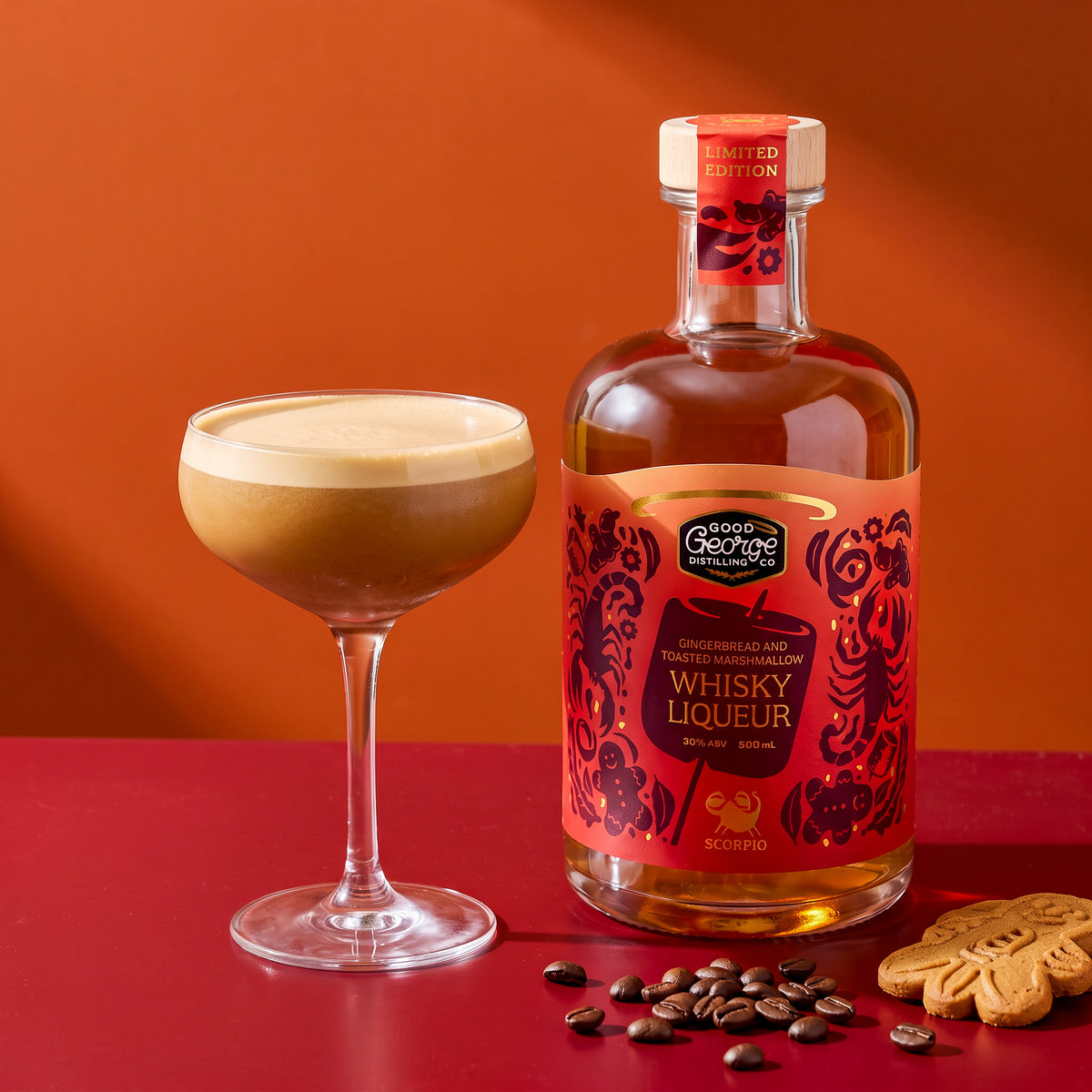 Gingerbread espresso martini in a coupe next to Good George Gingerbread and Toasted Marshmallow Whisky Liqueur, with coffee beans and a gingerbread biscuit