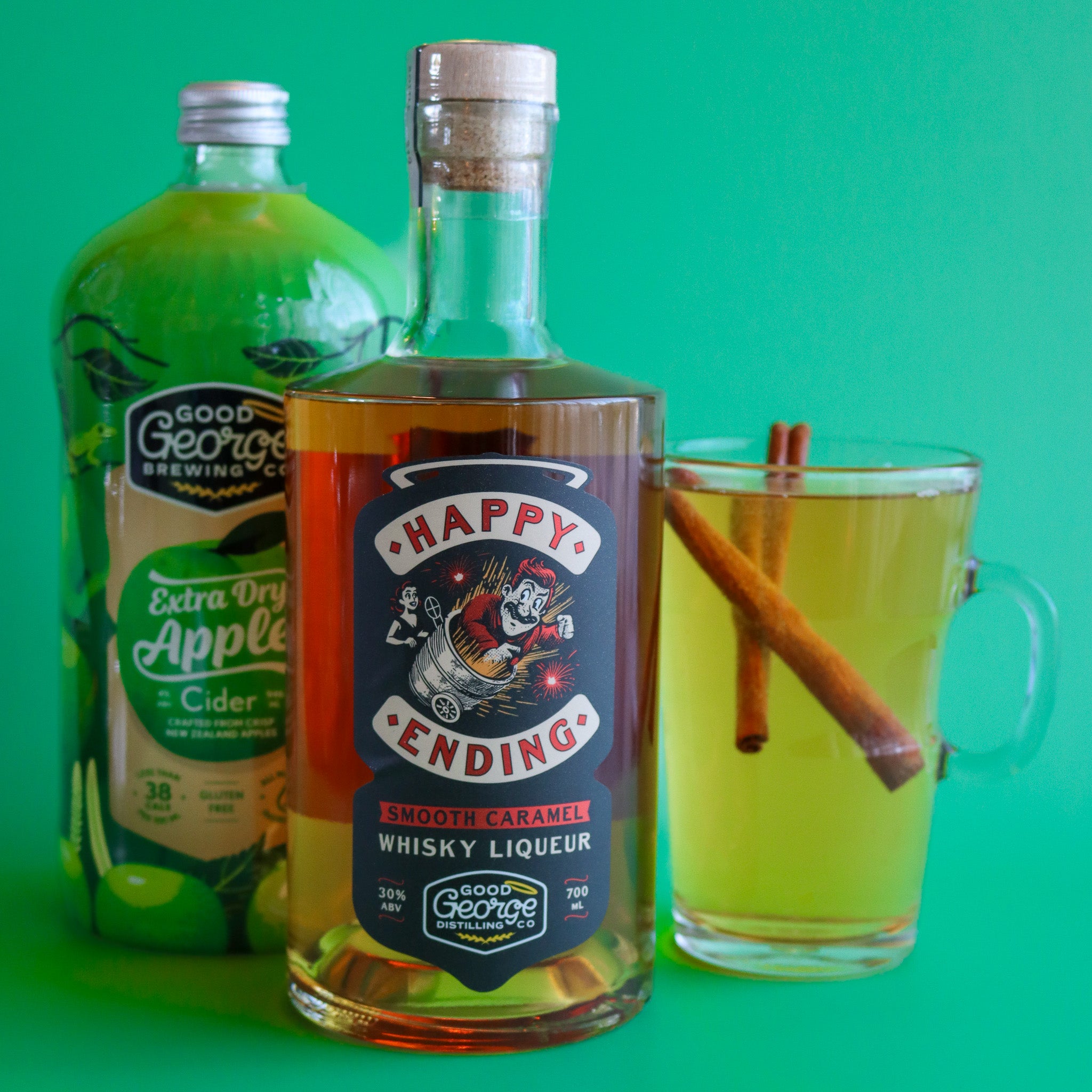 Bottle of 'Happy Ending' whisky liqueur with a glass of cider and cinnamon sticks on a green background