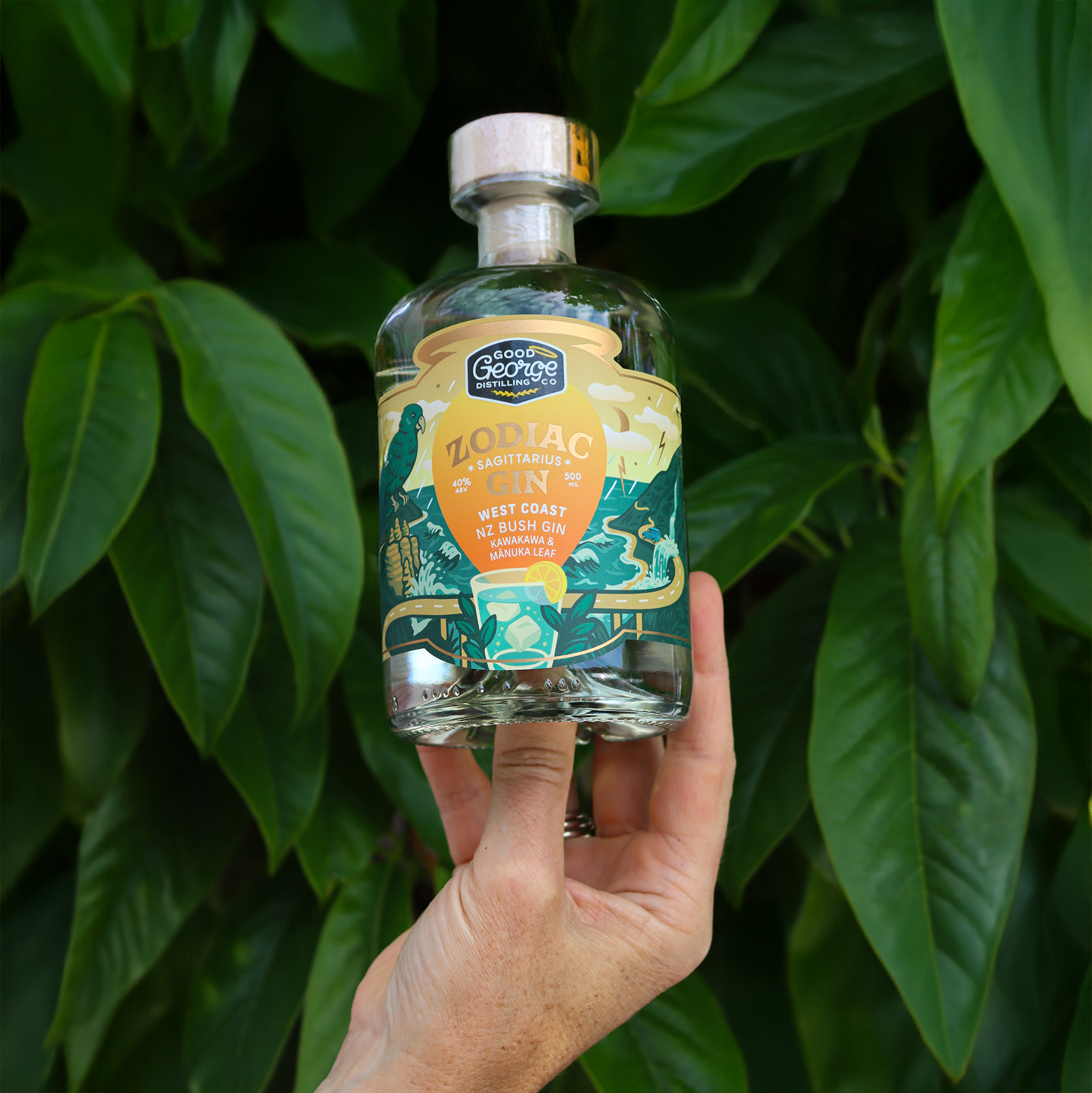Hand holding a bottle of George's Gin against a green leafy background