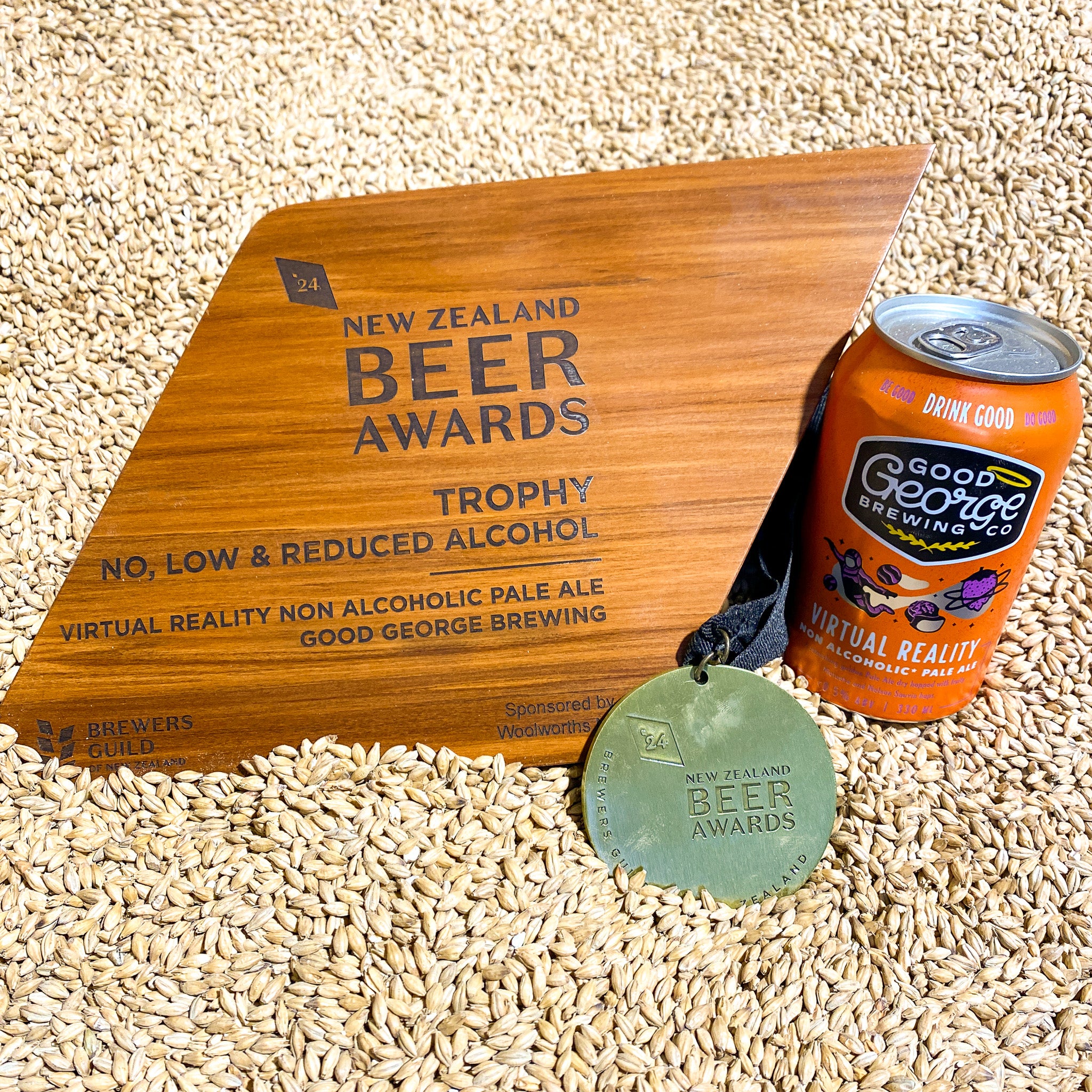 A can of Virtual Reality Non-Alcoholic Pale Ale by Good George Brewing Co. with a gold medal and trophy next to it in malt.