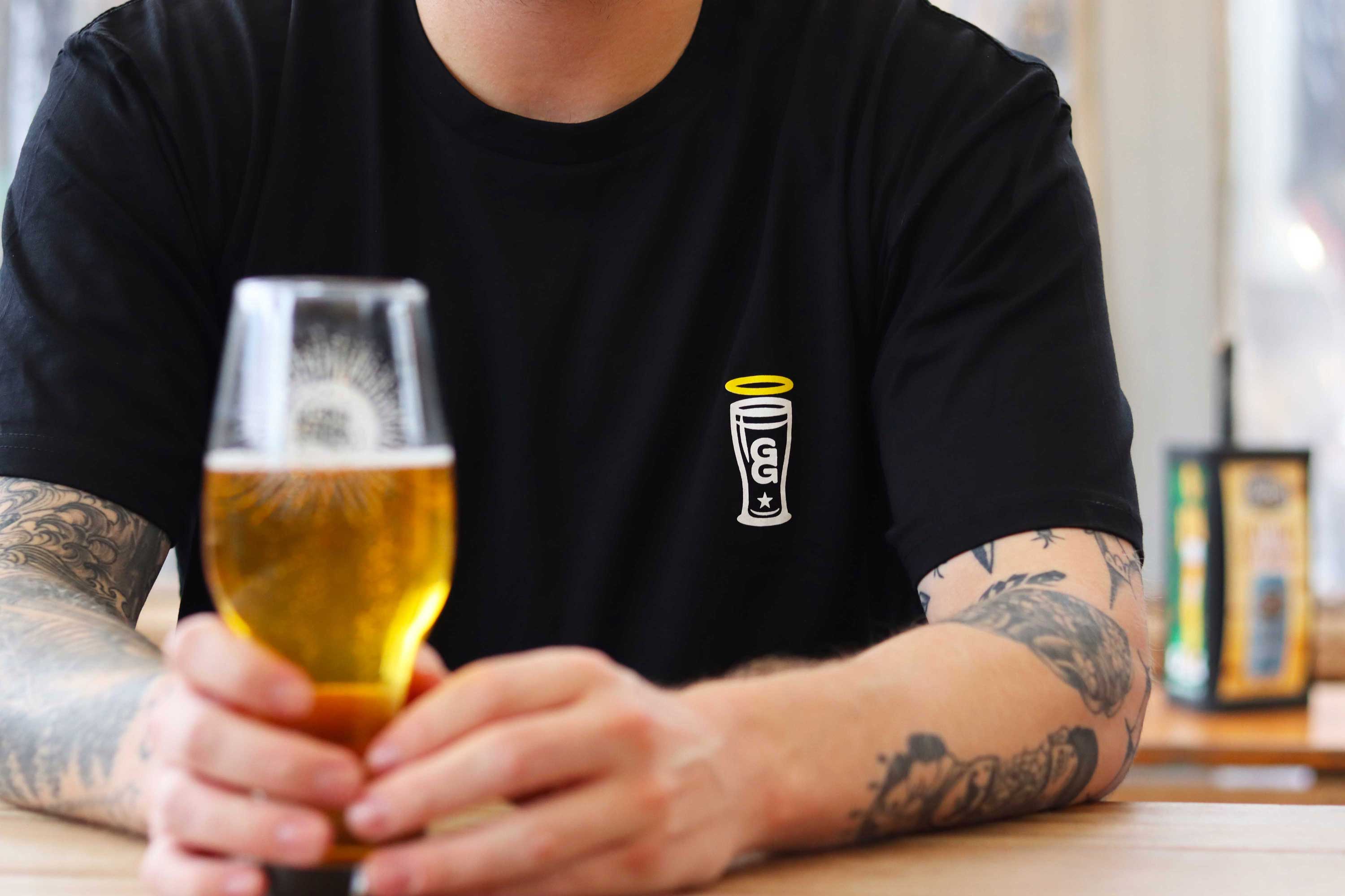 Black t-shirt with a small graphic of the GG halo on it with a beer in the foreground.