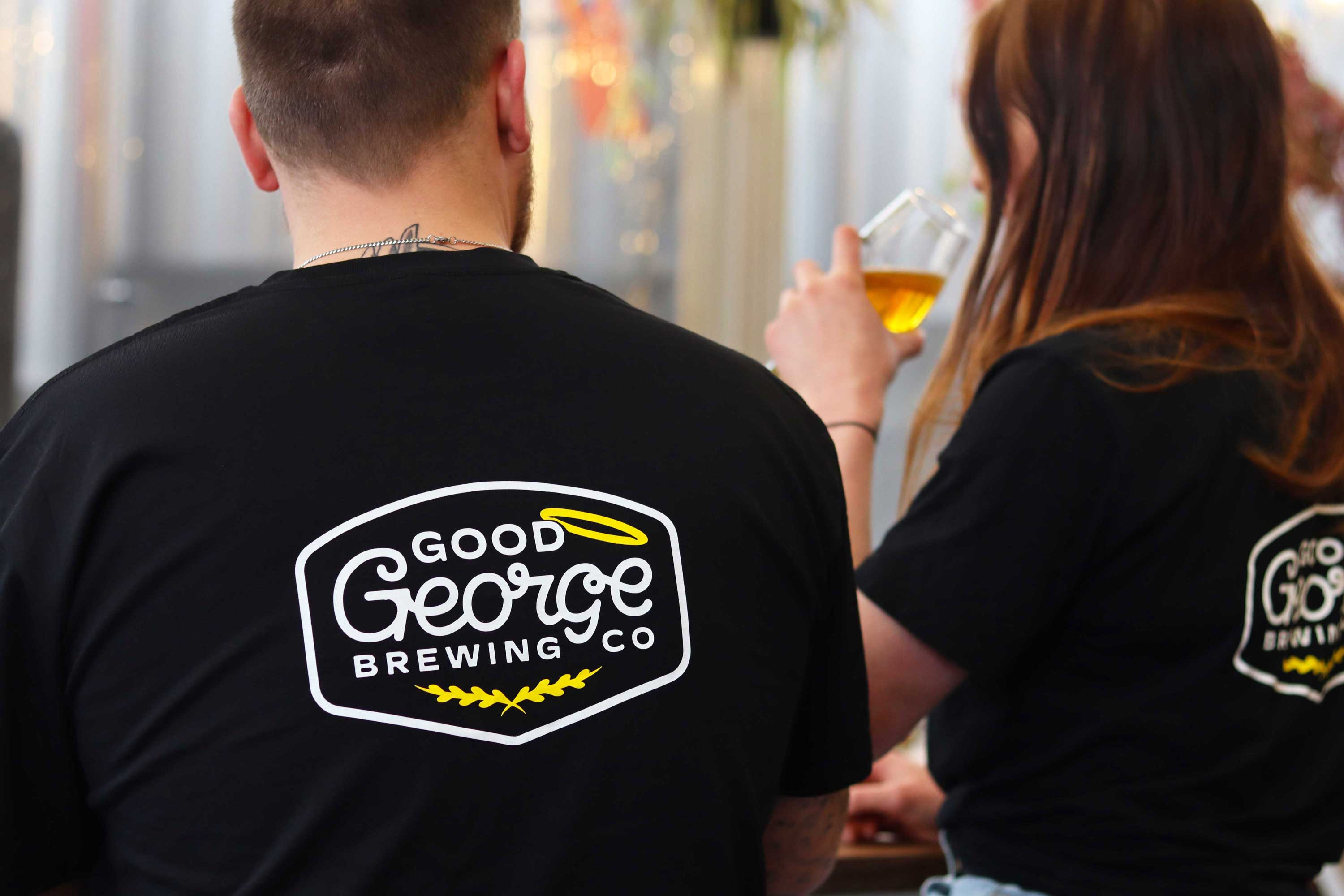 2 people wearing the Black t-shirt with a big graphic on the back, enjoying a beer