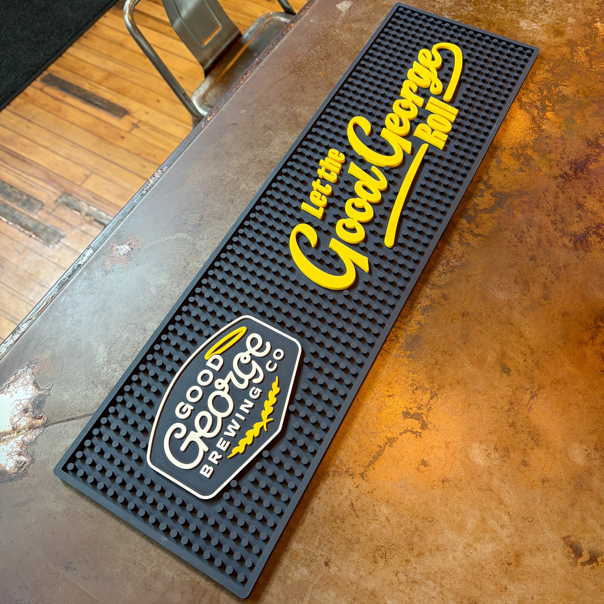 Bar mat with 'Good George Brewing Co.' logo on a metal surface