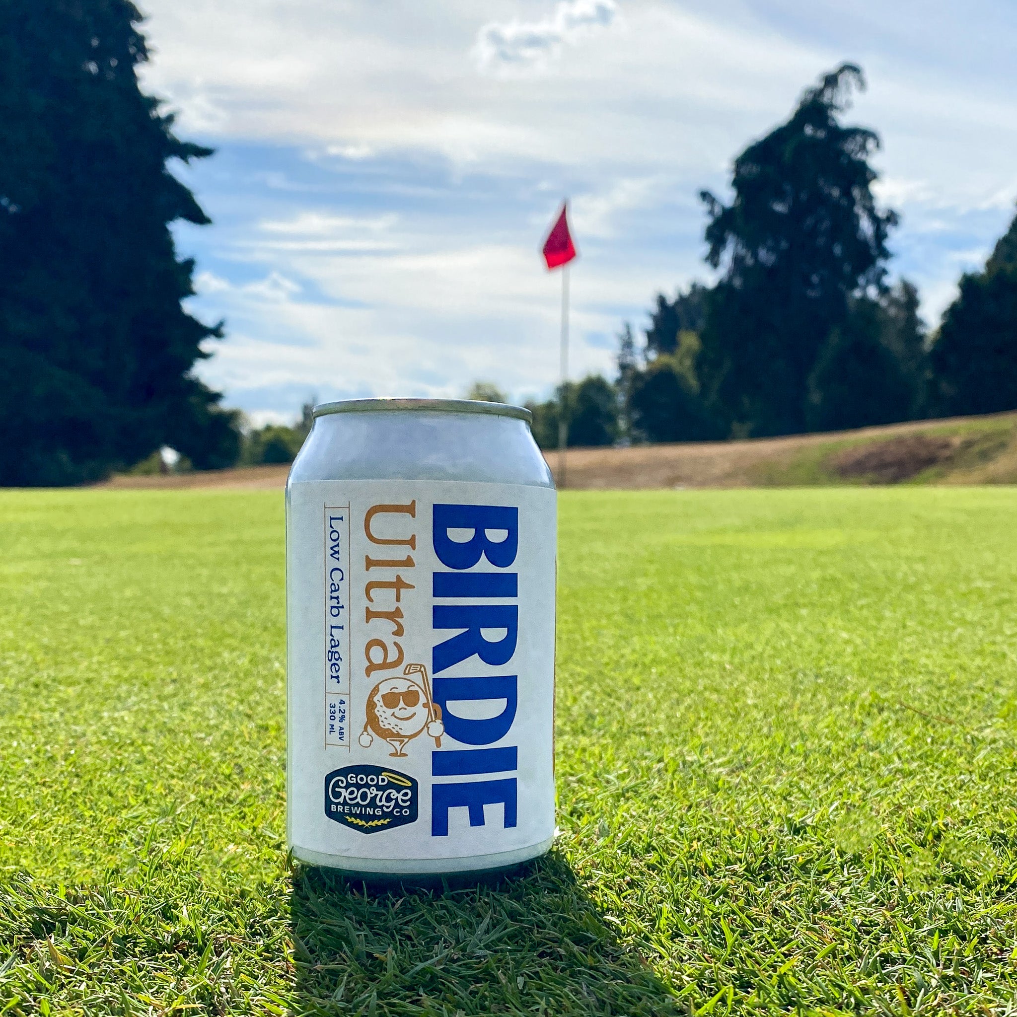 Can of Birdie Ultra on a golf course with trees and flag in the background