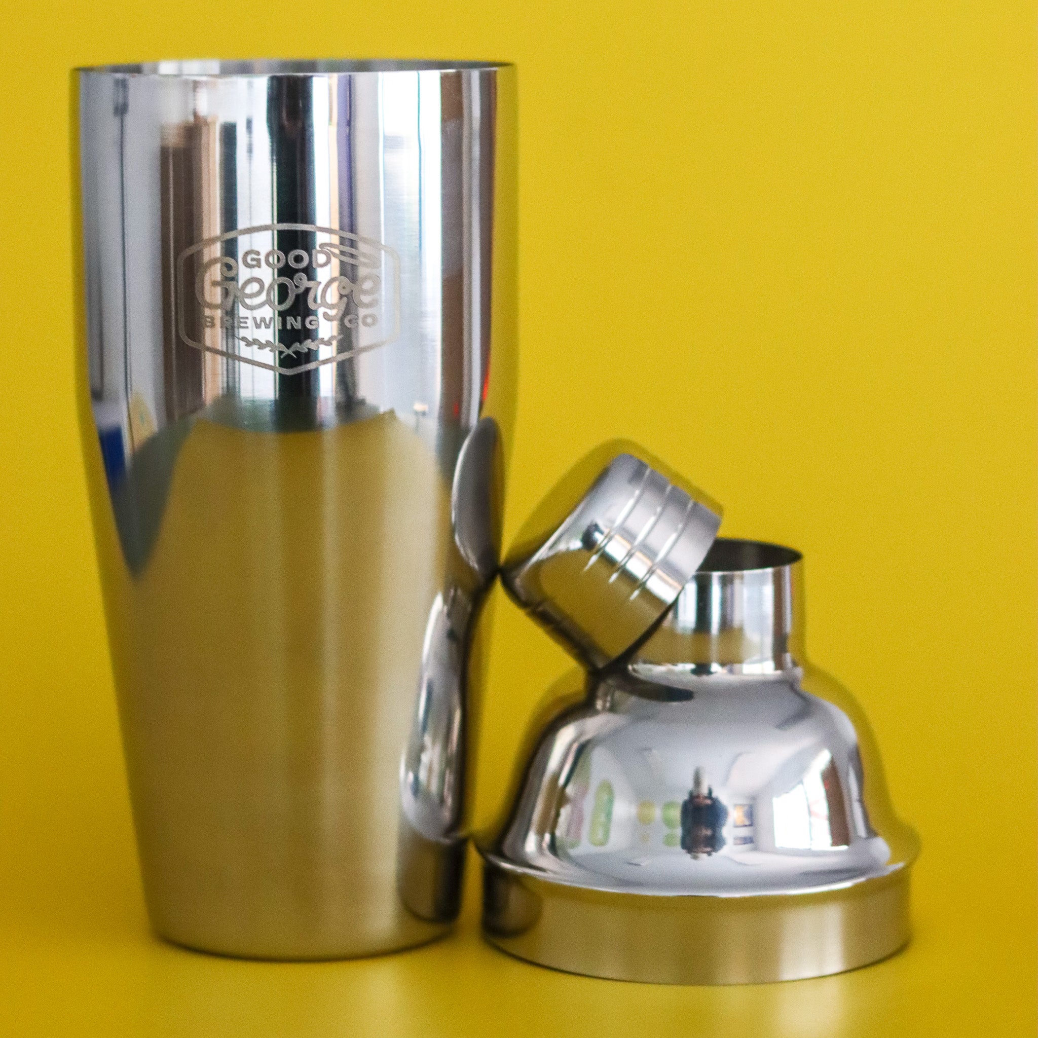 Metallic cocktail shaker with a lid on a yellow background