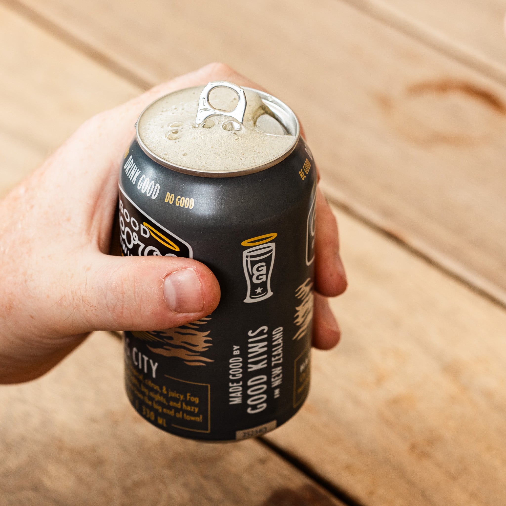 Hand holding a can of Good George Brewing Co. Fog City beer just been opened with foam on top