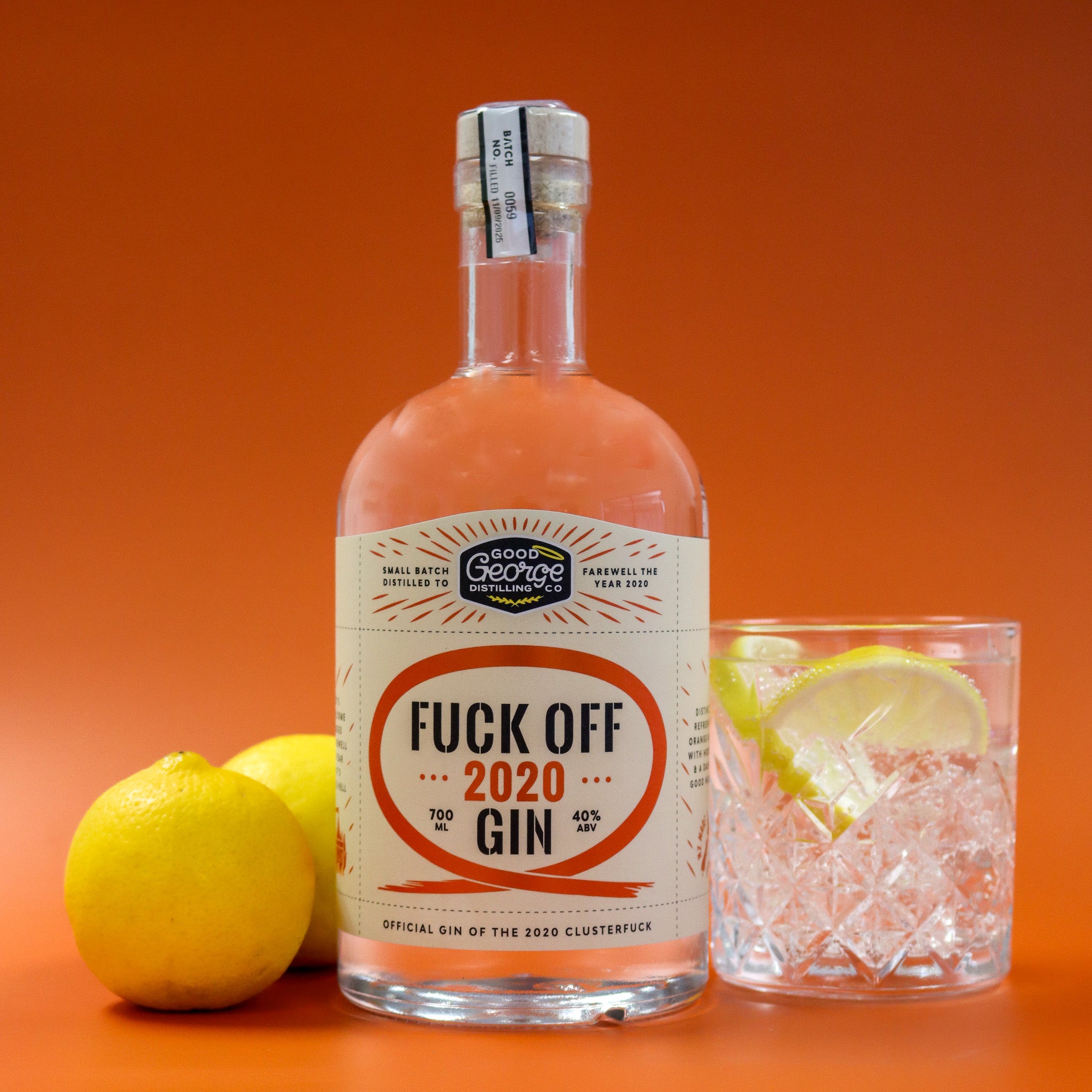 Bottle of 'Fuck Off 2020 Gin' with a glass of gin and tonic on an orange background