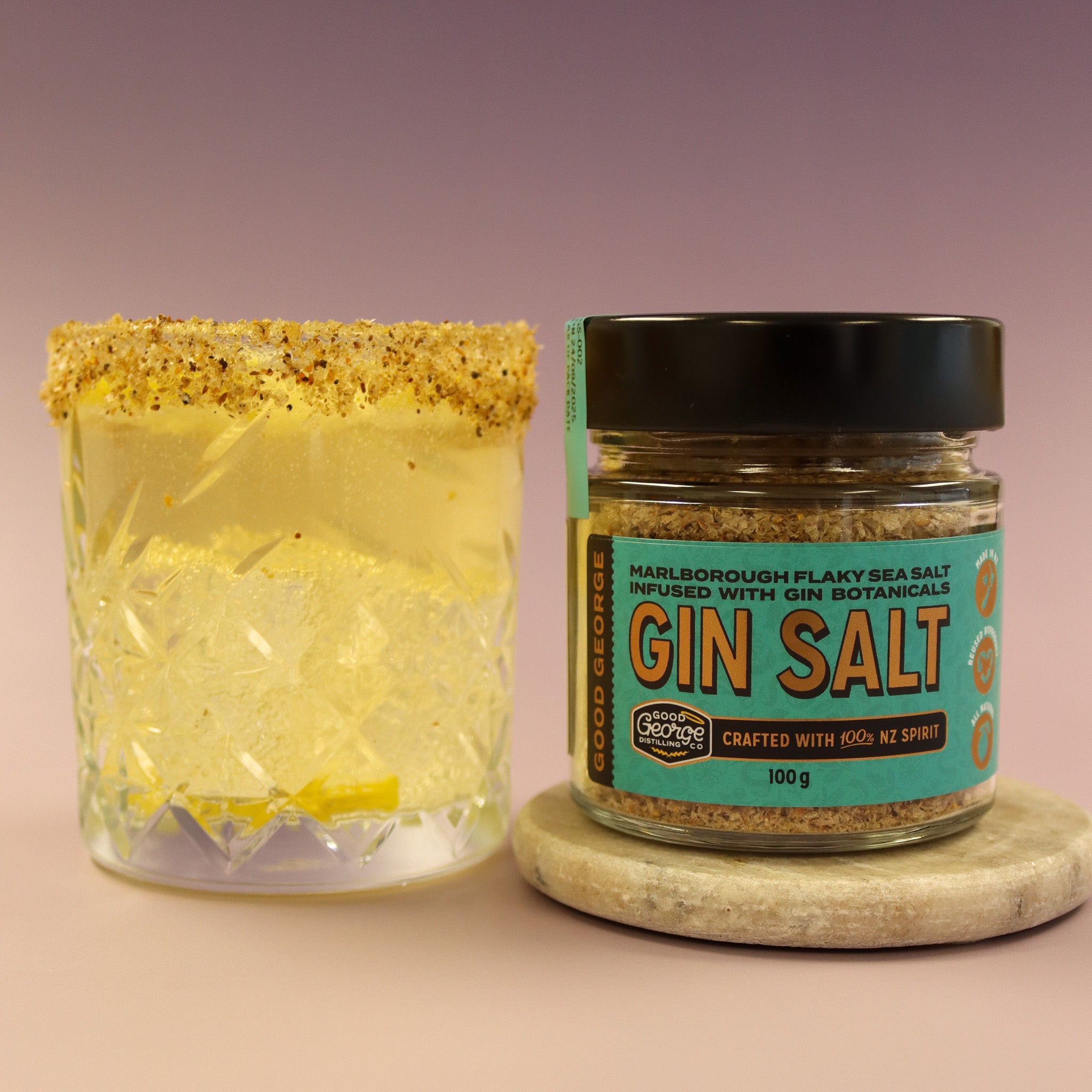 Jar of Gin Salt next to a cocktail with a salted rim on a pink background