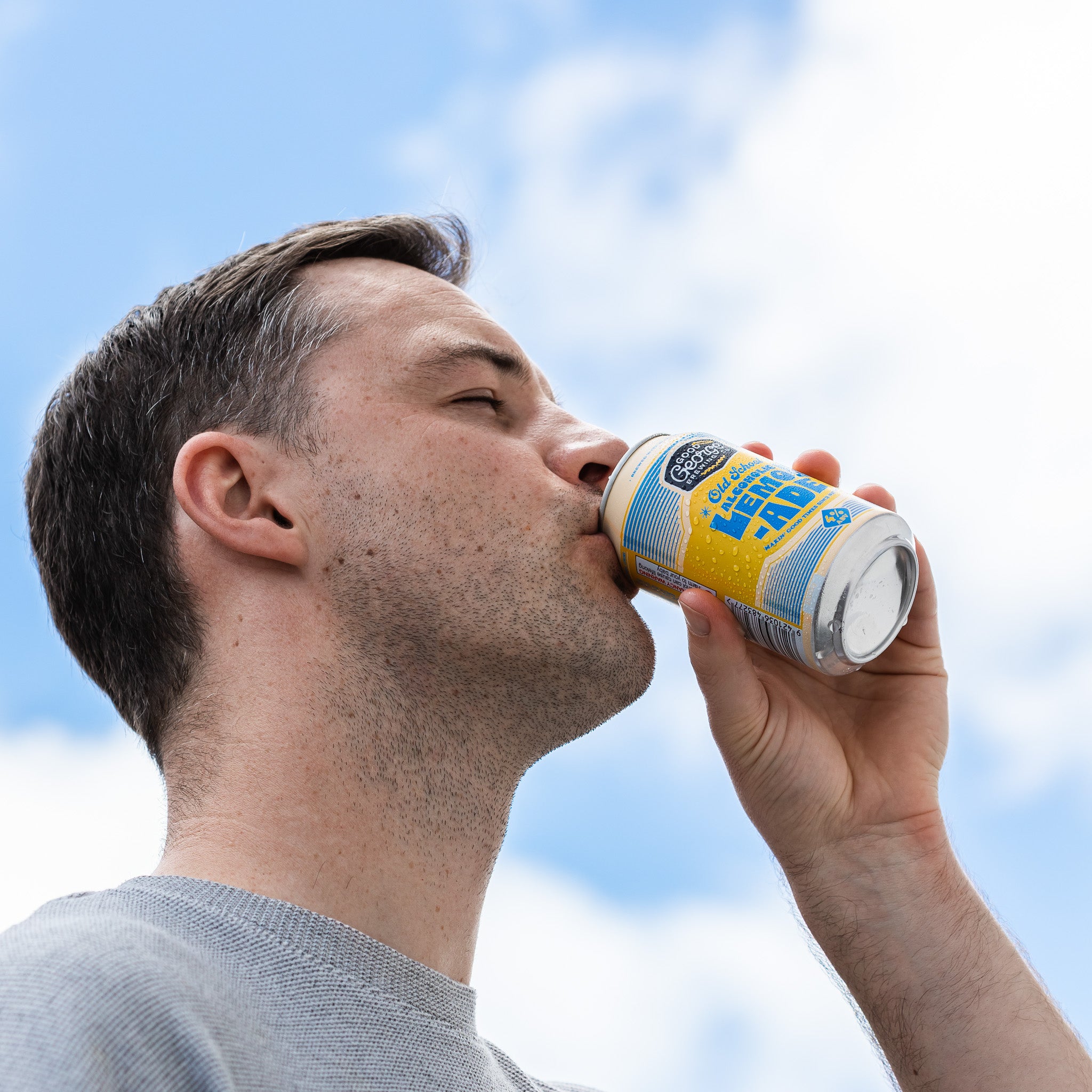 Man drinking from a can against a blue sky
