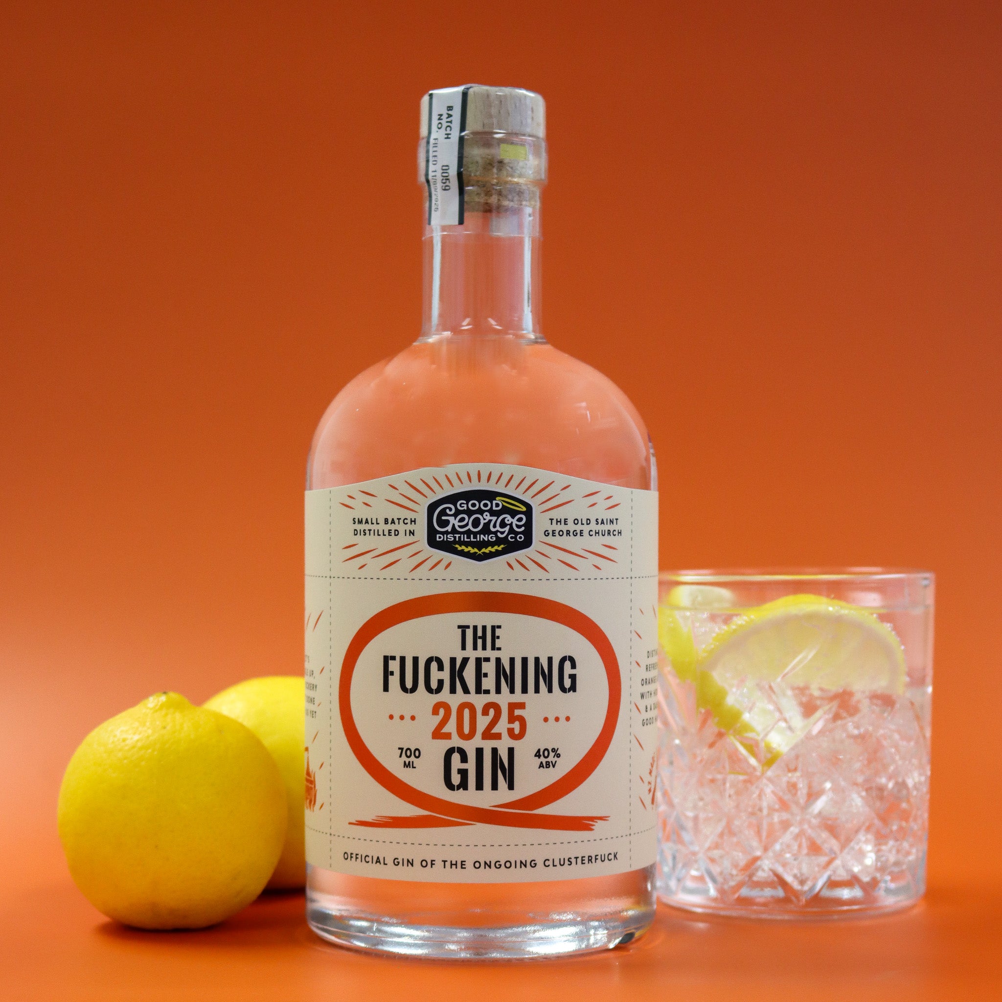 Bottle of 'The Fuckening 2025 Gin' with a glass of gin and tonic on an orange background