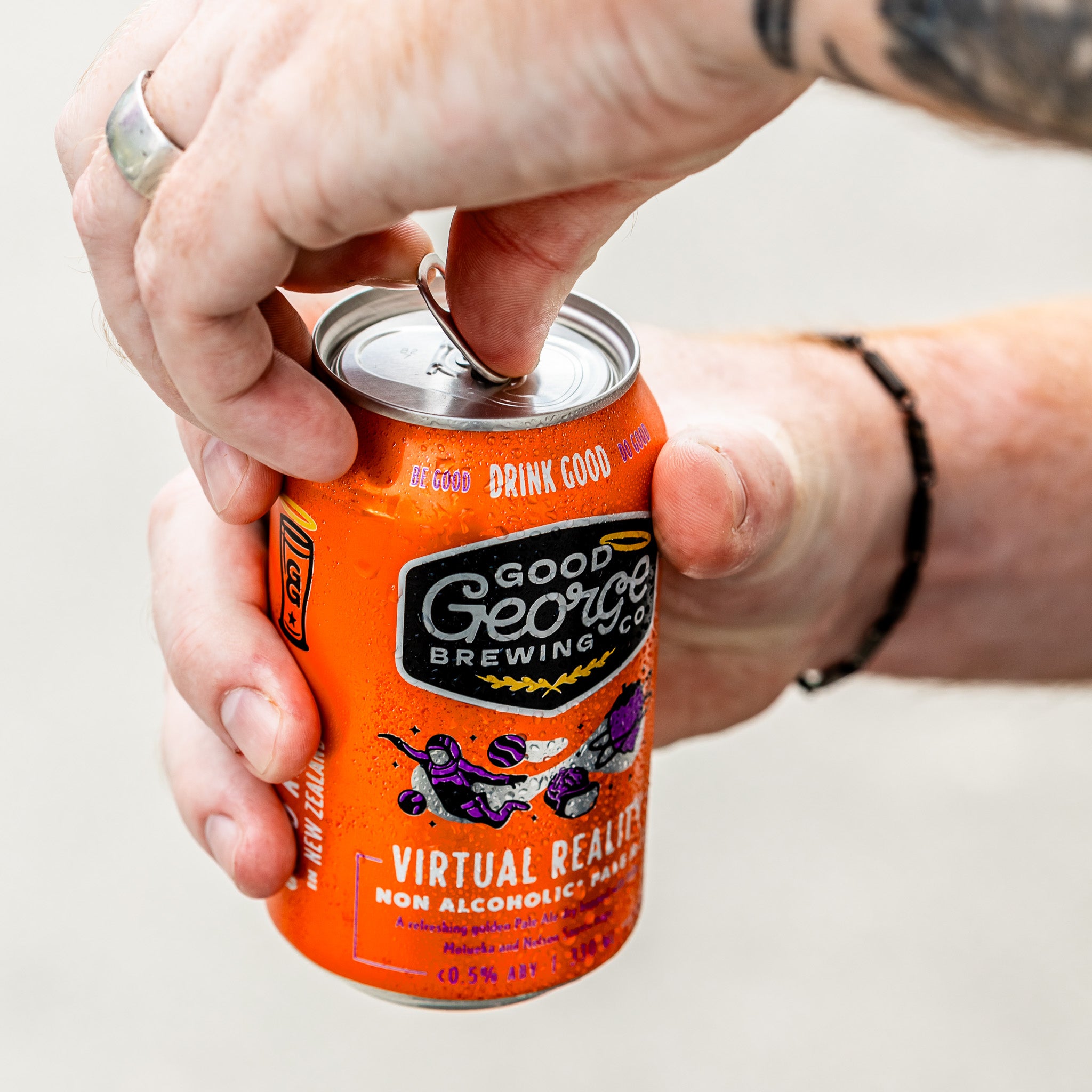 Hand holding a can of Good George Brewing Co. Virtual Reality Non-Alc Pale Ale about to get opened