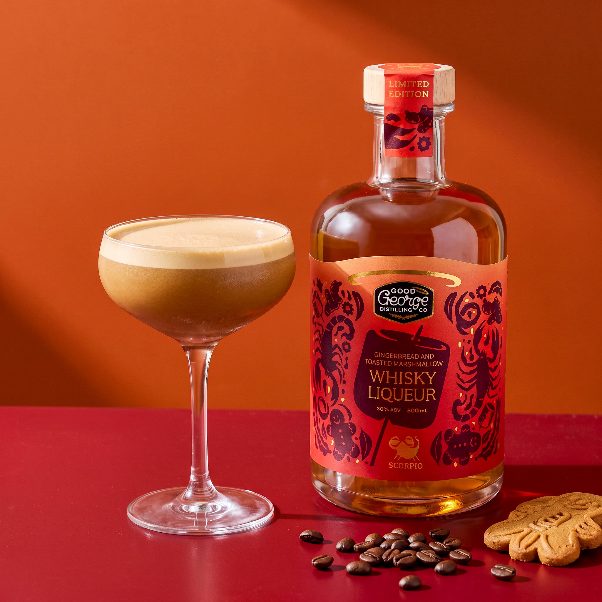 Gingerbread espresso martini in a coupe next to Good George Gingerbread and Toasted Marshmallow Whisky Liqueur, with coffee beans and a gingerbread biscuit